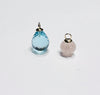 Atelier Beatrix Wolter-Anhänger  aus facettiertem himmelblauen Topas in Tropfenform  mit einer Anhängerkappe und Öse aus 750 Gold. Neben einem Anhänger aus gravierter Rosenquarz in Pumpkinform mit Anhängerkappe und Öse aus 750 Gold I 18K Gold.