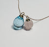 Atelier Beatrix Wolter-Anhänger  aus facettiertem himmelblauen Topas in Tropfenform  mit einer Anhängerkappe und Öse aus 750 Gold. Neben einem Anhänger aus gravierter Rosenquarz in Pumpkinform mit Anhängerkappe und Öse aus 750 Gold I 18K Gold an einer 750 Gold Kette.