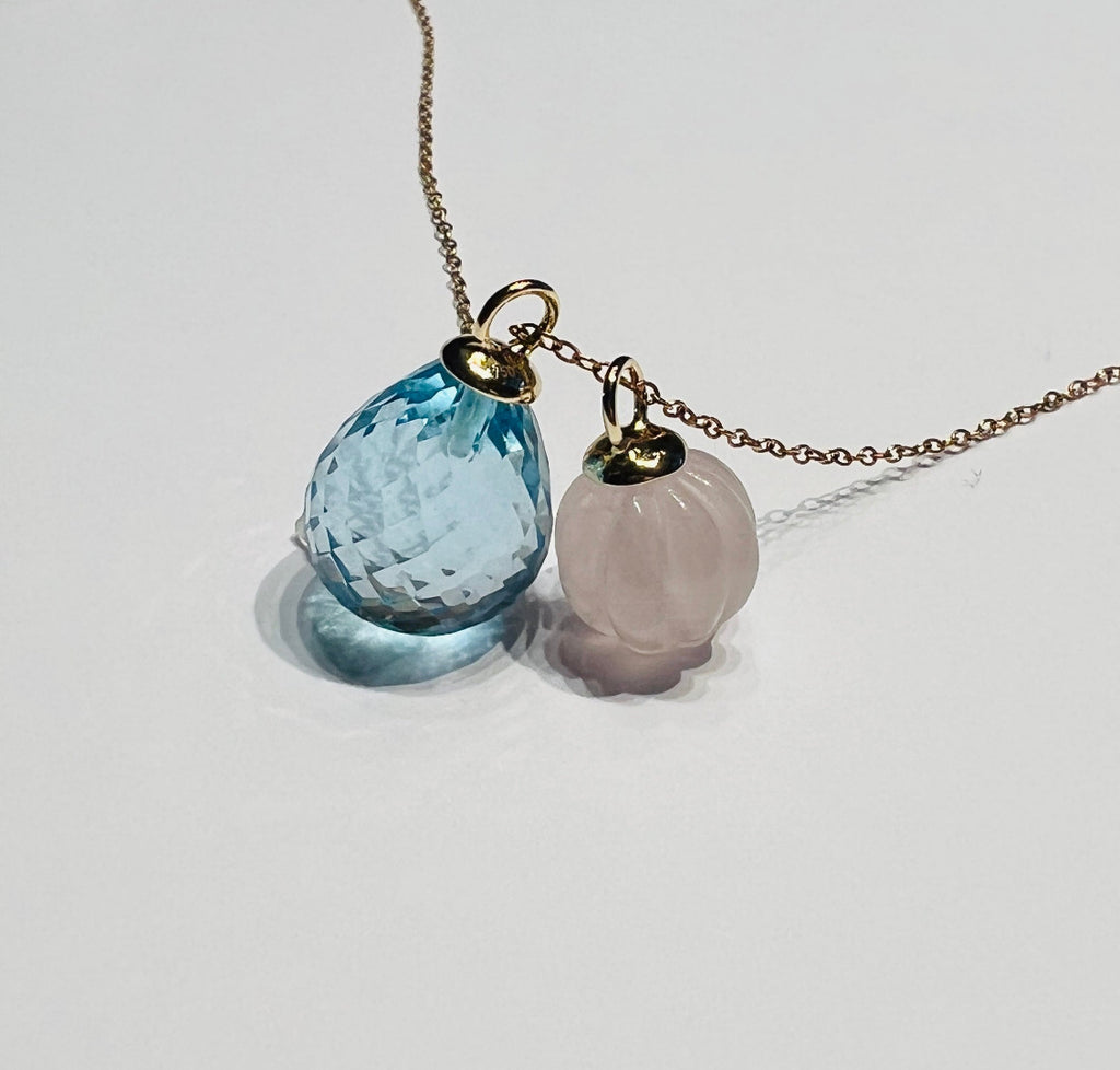 Atelier Beatrix Wolter-Anhänger  aus facettiertem himmelblauen Topas in Tropfenform  mit einer Anhängerkappe und Öse aus 750 Gold. Neben einem Anhänger aus gravierter Rosenquarz in Pumpkinform mit Anhängerkappe und Öse aus 750 Gold I 18K Gold an einer 750 Gold Kette.