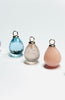 Atelier Beatrix Wolter Drei Kettenangänger jeweils mit einer Anhängerkappe und Öse gefertigt aus 750 Gold. Ganz vorne rechts ein rosa Andenopal-Tropfen, in der Mitte ein Rosenquarz-Tropfen und hinten links ein facettierter Topas-Tropfen 